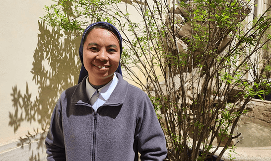 Sister Genevieve smiling next to plants