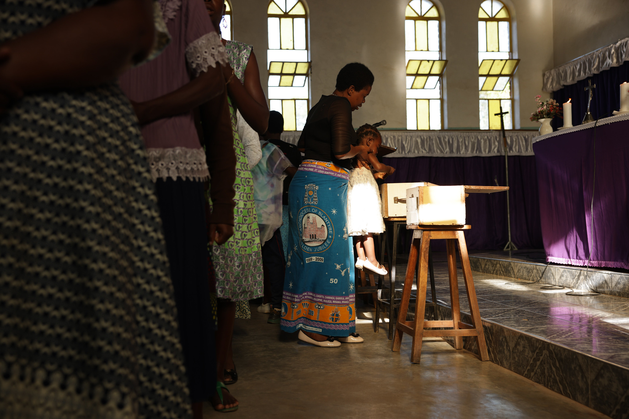 the faithful processed to the front of the church to give their offerings, placing them in multiple boxes set at the foot of the sanctuary.