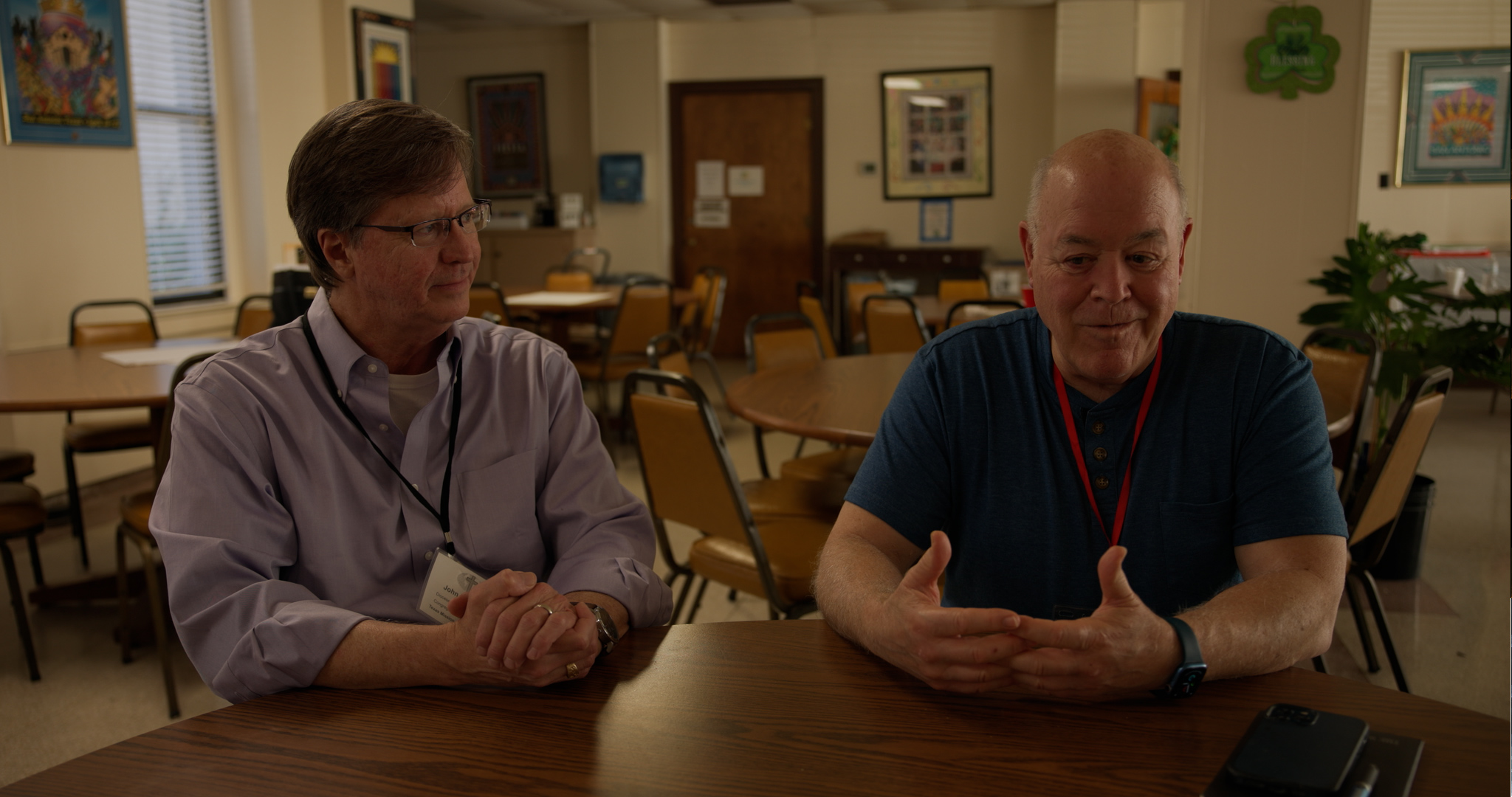 Two men sitting at a table in a school cafeteria