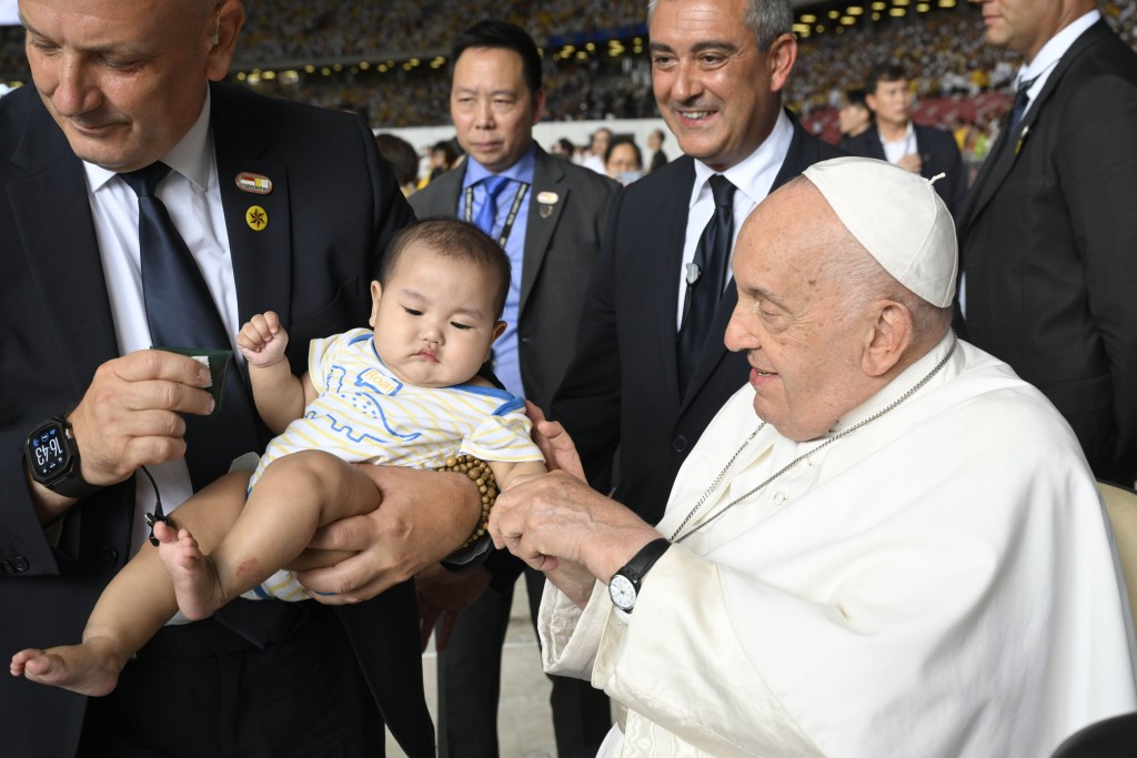 Pope Francis greets a child before celebrating Mass at Singapore's National Stadium.