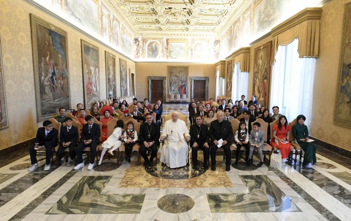 Pope Francis poses for a photograph during a meeting at the Vatican Dec. 19, 2024, with representatives of the Pontifical Mission Societies and benefactors from Vietnam who live in the United States. Sitting to the left of the pope is Archbishop Emilio Nappa, president of the Pontifical Mission Societies International. (CNS photo/Vatican Media)