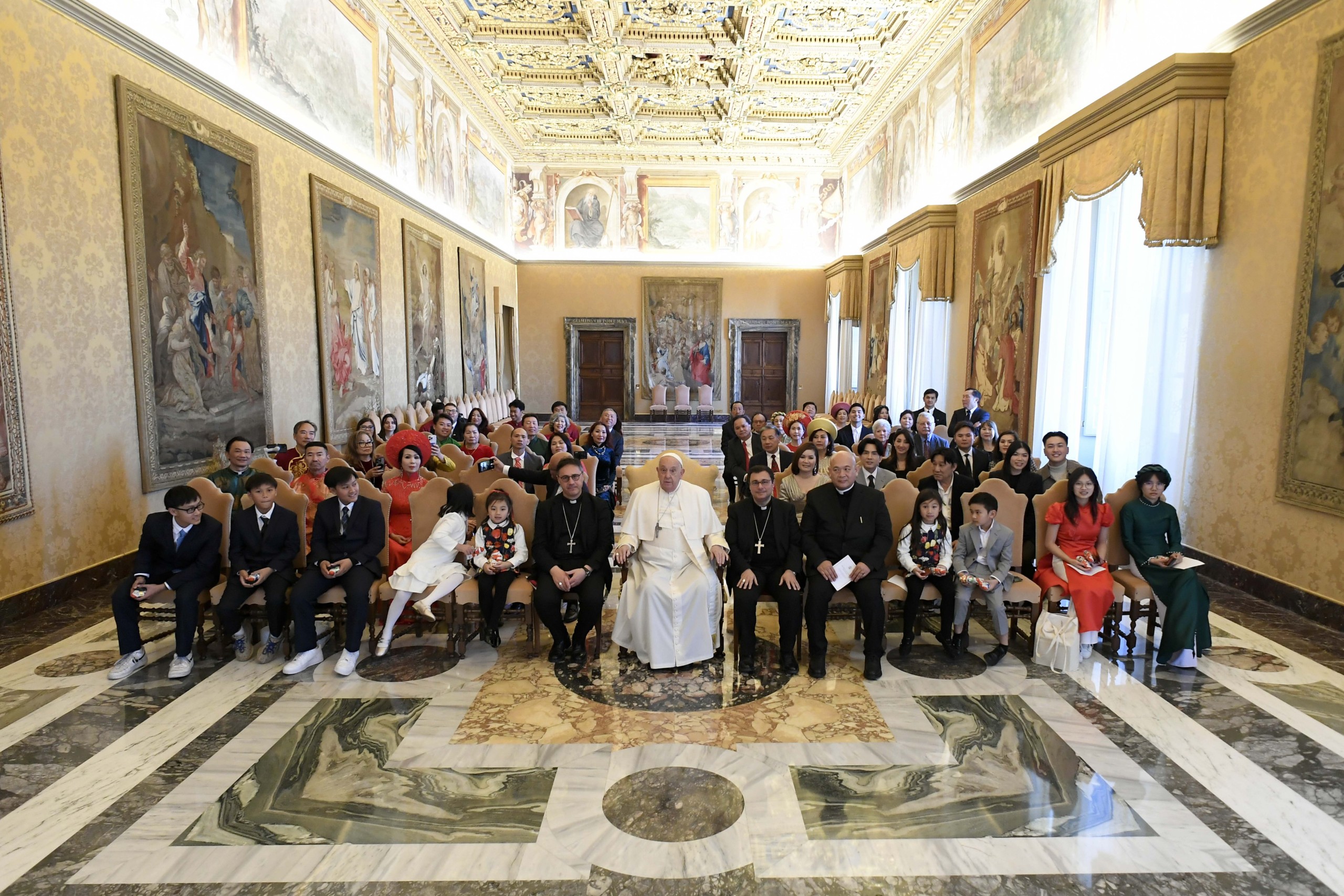 Pope Francis poses for a photograph during a meeting at the Vatican Dec. 19, 2024, with representatives of the Pontifical Mission Societies and benefactors from Vietnam who live in the United States. Sitting to the left of the pope is Archbishop Emilio Nappa, president of the Pontifical Mission Societies International. (CNS photo/Vatican Media)